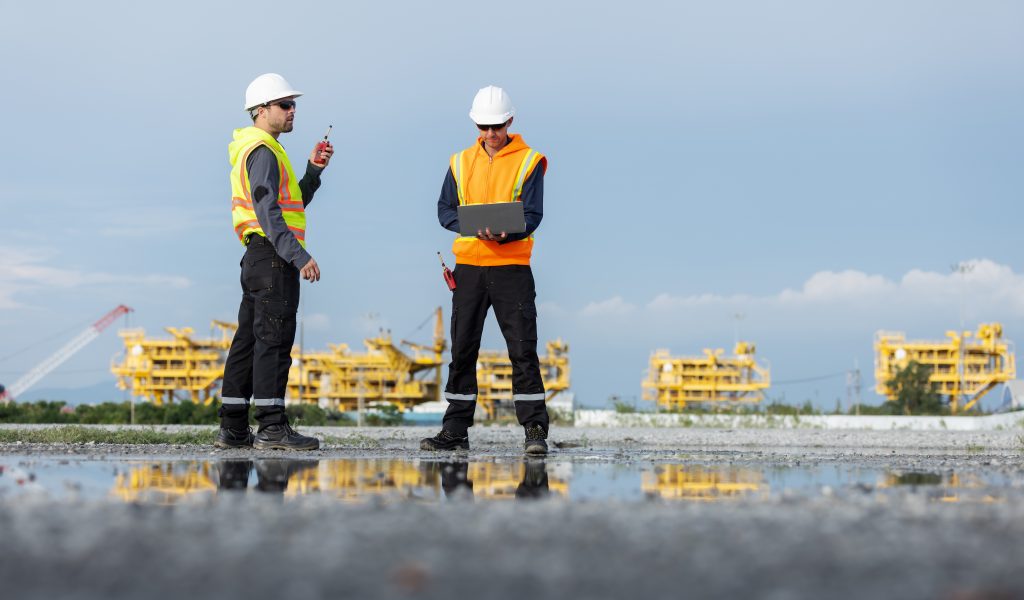 Two,Engineers,In,Safety,Gear,Stand,On,A,Reflective,Surface